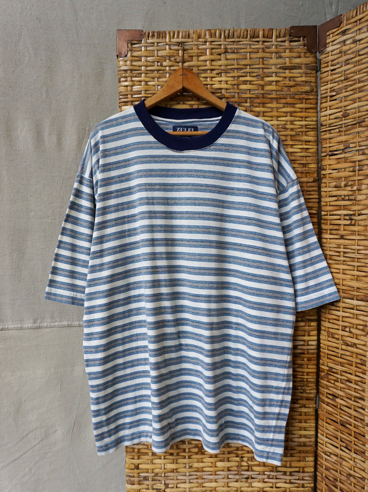 Blue and white striped shirt on a hanger against a textured wall.