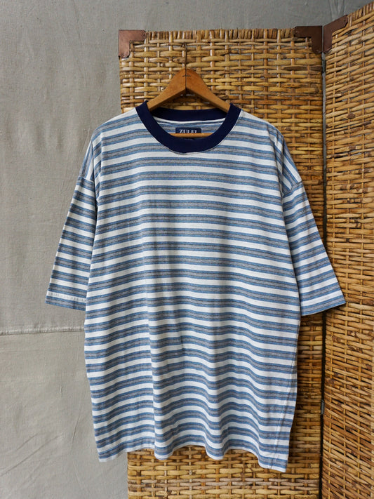 Blue and white striped shirt on a hanger against a textured wall.